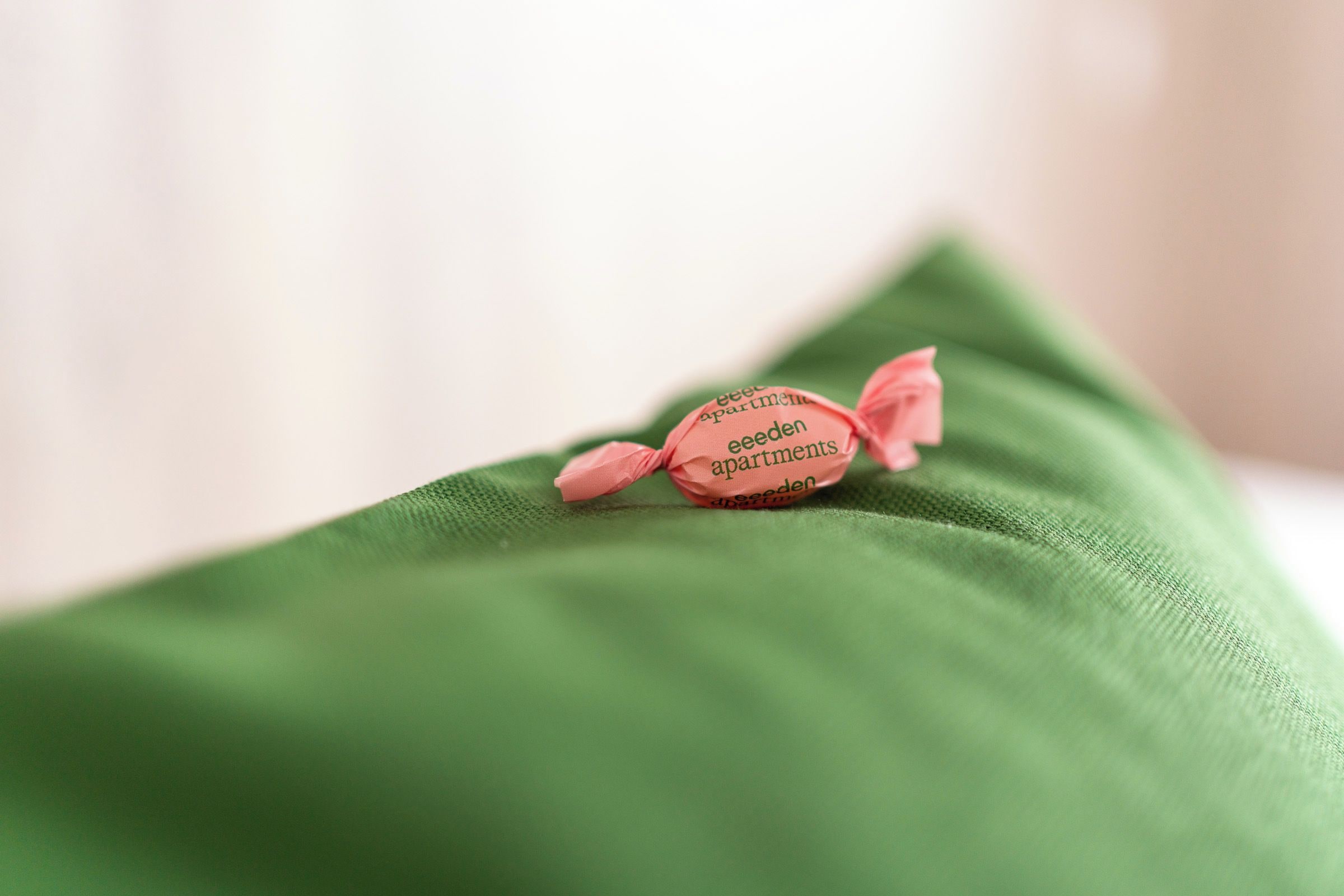Un caramelo rosa sobre un cojín verde.