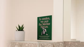 A bathroom with a white sink, a towel, a green sign, and a potted plant.