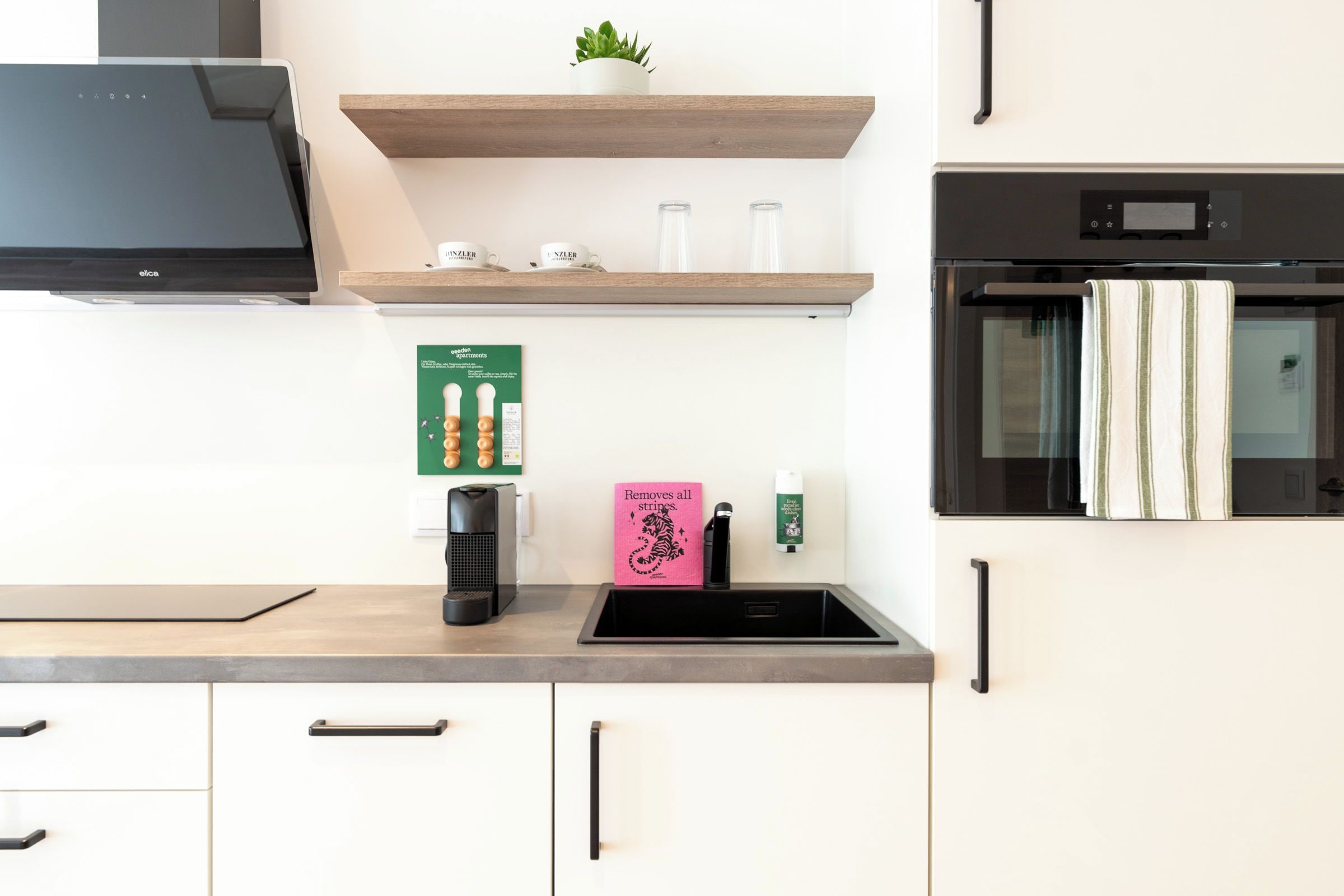 A modern kitchen with a built-in oven, a coffee machine, and a sink.