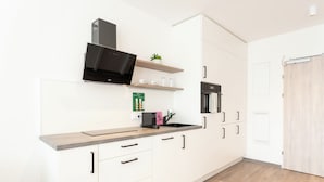 Una cocina moderna con armarios blancos, una campana extractora negra y un horno empotrado.