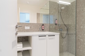A modern bathroom with a glass shower enclosure, a white vanity with a mirror, and a towel rack. - eeeden apartments Wien 10 (Vienna)