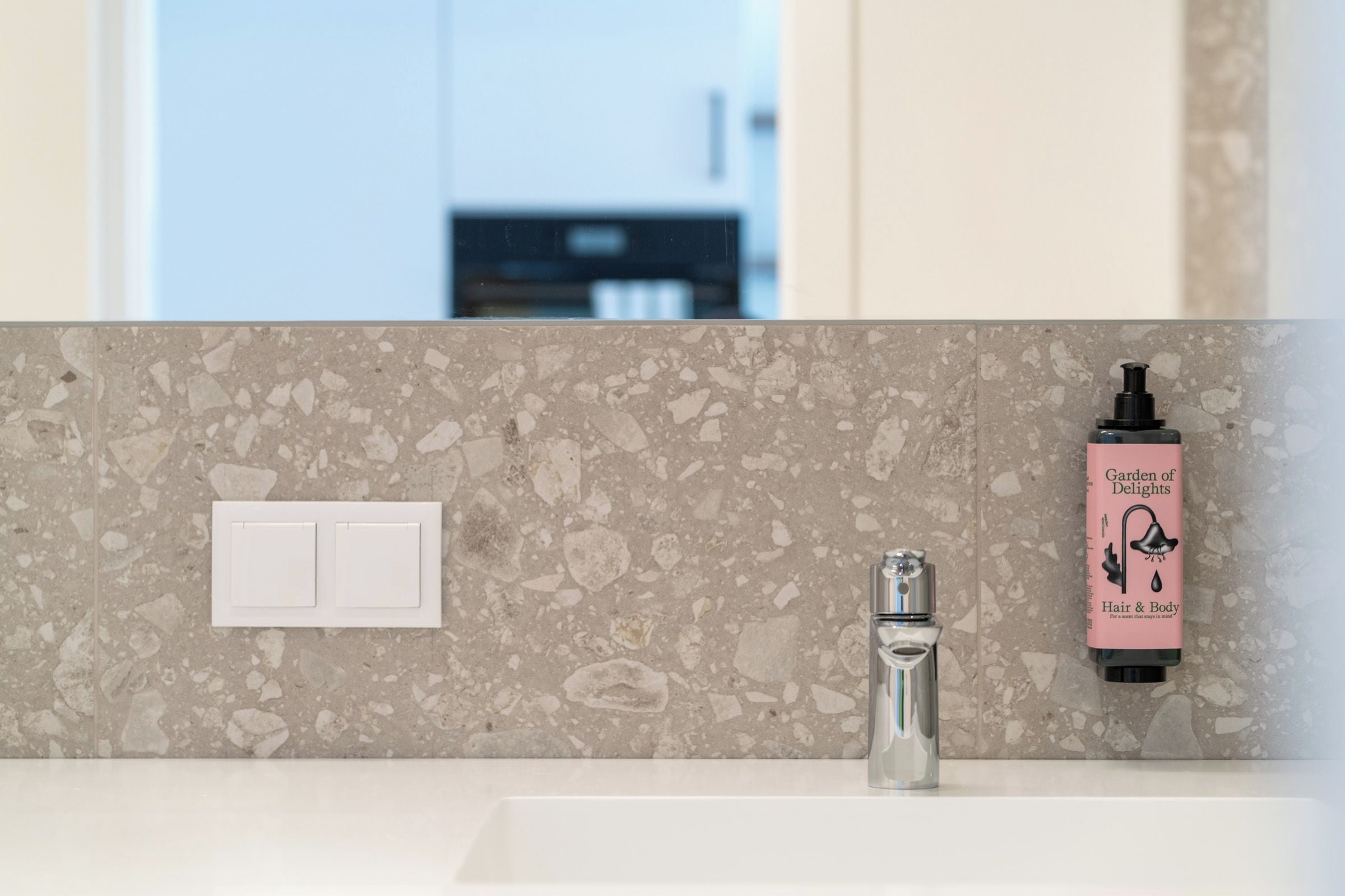 Un baño con un lavamanos blanco, un espejo y un dispensador de jabón en la pared.