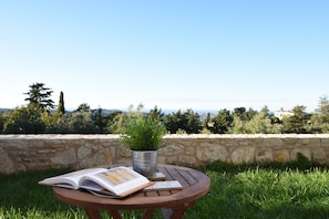 A round wooden table with an open book and a potted plant. - Mon Emvasia Margarites Villa A (Rethymno)