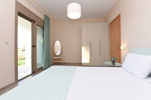Une chambre à coucher comprenant un lit, une table de chevet, un miroir, une armoire et une table ornée d’un vase de fleurs.
