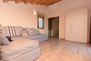 A modern living room with a sofa set, a wardrobe, and a glass door leading to another room. - Mon Emvasia Margarites Villa A (Rethymno)