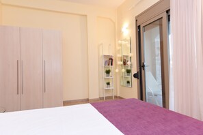 A bedroom with a bed, a wardrobe, a vanity with a mirror, and a door leading to a balcony. - Mon Emvasia Margarites Villa B (Rethymno)