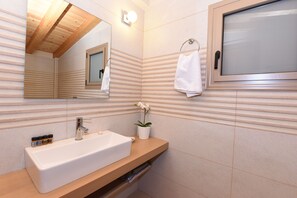Ein modernes Badezimmer mit einem großen Spiegel, einem Waschbecken und einem Handtuchhalter.
