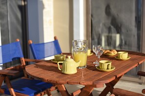 Ein Holztisch, gedeckt mit gelben Tassen, einer Glasgießkanne und einem Teekessel, was eine Frühstückssituation andeutet.