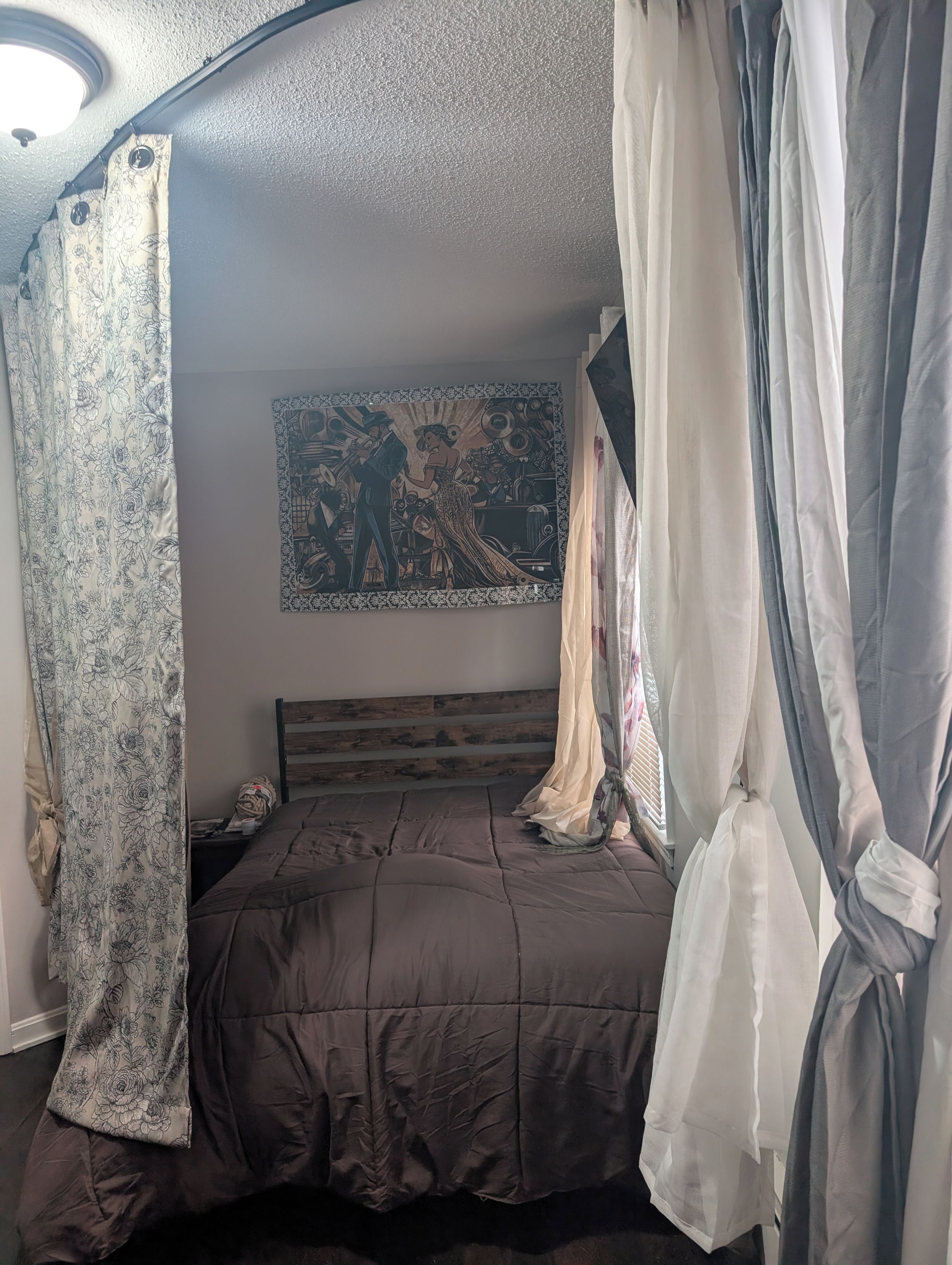 Une chambre à coucher avec un lit, des rideaux et une tapisserie murale.