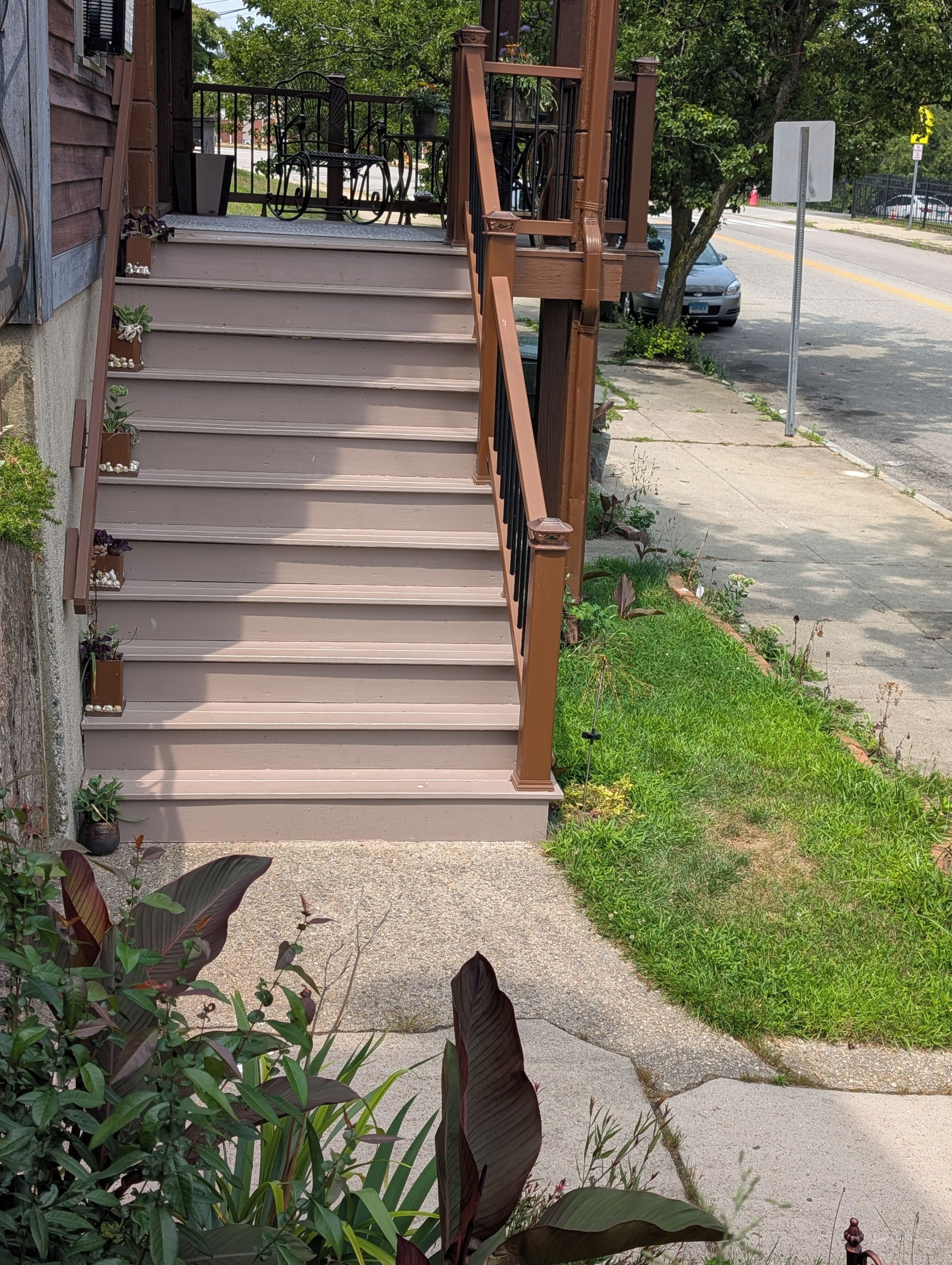 A set of outdoor stairs leading to a building entrance, surrounded by greenery and a sidewalk.