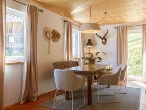 Ein Essbereich mit einem Holztisch, vier Stühlen, einer Lampe und einem an der Wand befestigten Haken für Hüte.