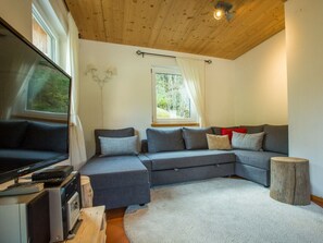 Ein modernes Wohnzimmer mit einem Ecksofa, einem Flachbildfernseher und einer Holzbalkendecke.