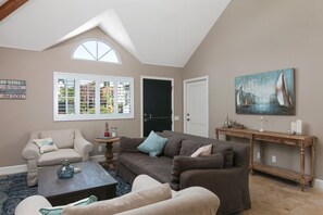 A living room with a high ceiling, a large window, a dark door, and a painting of sailboats. - 25% Oct 22-25, Perfect For Families, Walk 2 Beach! (Ventura)