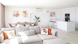 Ein modernes Wohnzimmer mit einem Ecksofa, einem Esstisch und einer Küchenzeile.