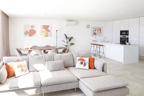 A modern living room with a sectional sofa, a dining table, and a kitchen area. - Luxury 3-bedroom Privilege Casa do Colhereiro with Private Pool (Luz)