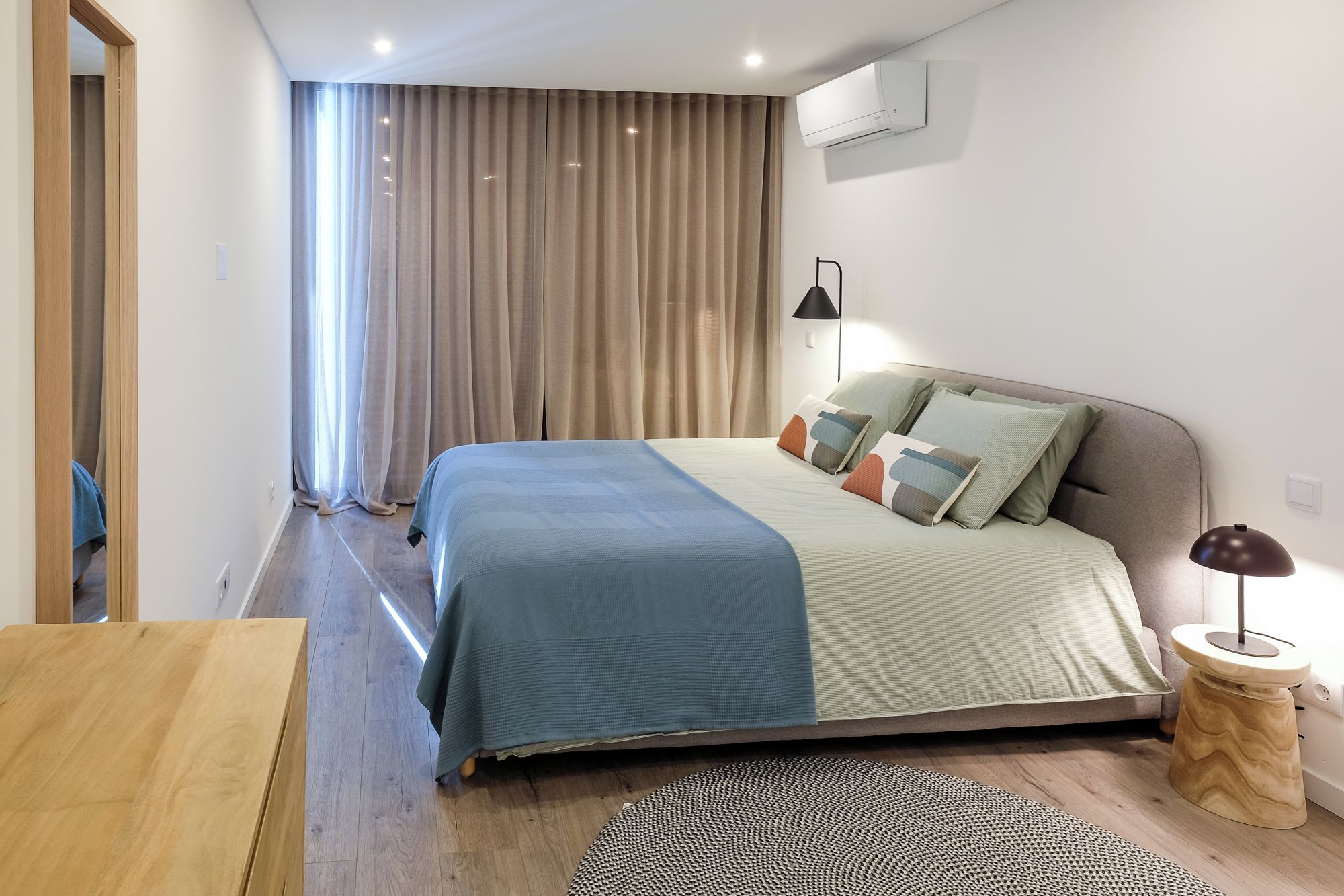Ein modernes Schlafzimmer mit einem Bett, einer Nachttischlampe und einem kleinen Holfnachtkästchen.