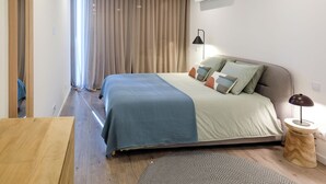 Ein modernes Schlafzimmer mit einem Bett, einer Nachttischlampe und einem kleinen Holfnachtkästchen.