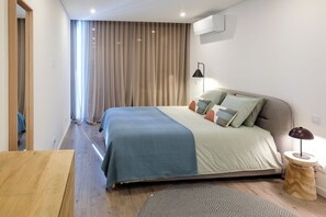 A modern bedroom with a bed, bedside lamp, and a small wooden side table. - Luxury 3-bedroom Privilege Casa do Colhereiro with Private Pool (Luz)