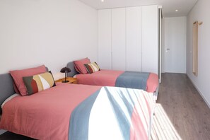 A bedroom with two beds, a bedside table with a lamp, and a wardrobe. - Luxury 3-bedroom Privilege Casa do Colhereiro with Private Pool (Luz)