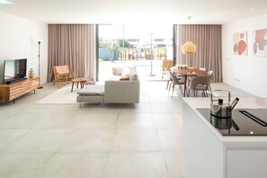 A modern living room with a sofa, TV, and dining area. - Luxury 3-bedroom Privilege Casa do Colhereiro with Private Pool (Luz)