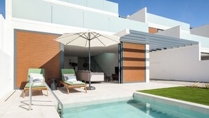 Ein moderner Poolbereich im Freien mit Liegestühlen, einer gläsernen Veranda und freiem Blick auf den Pool.