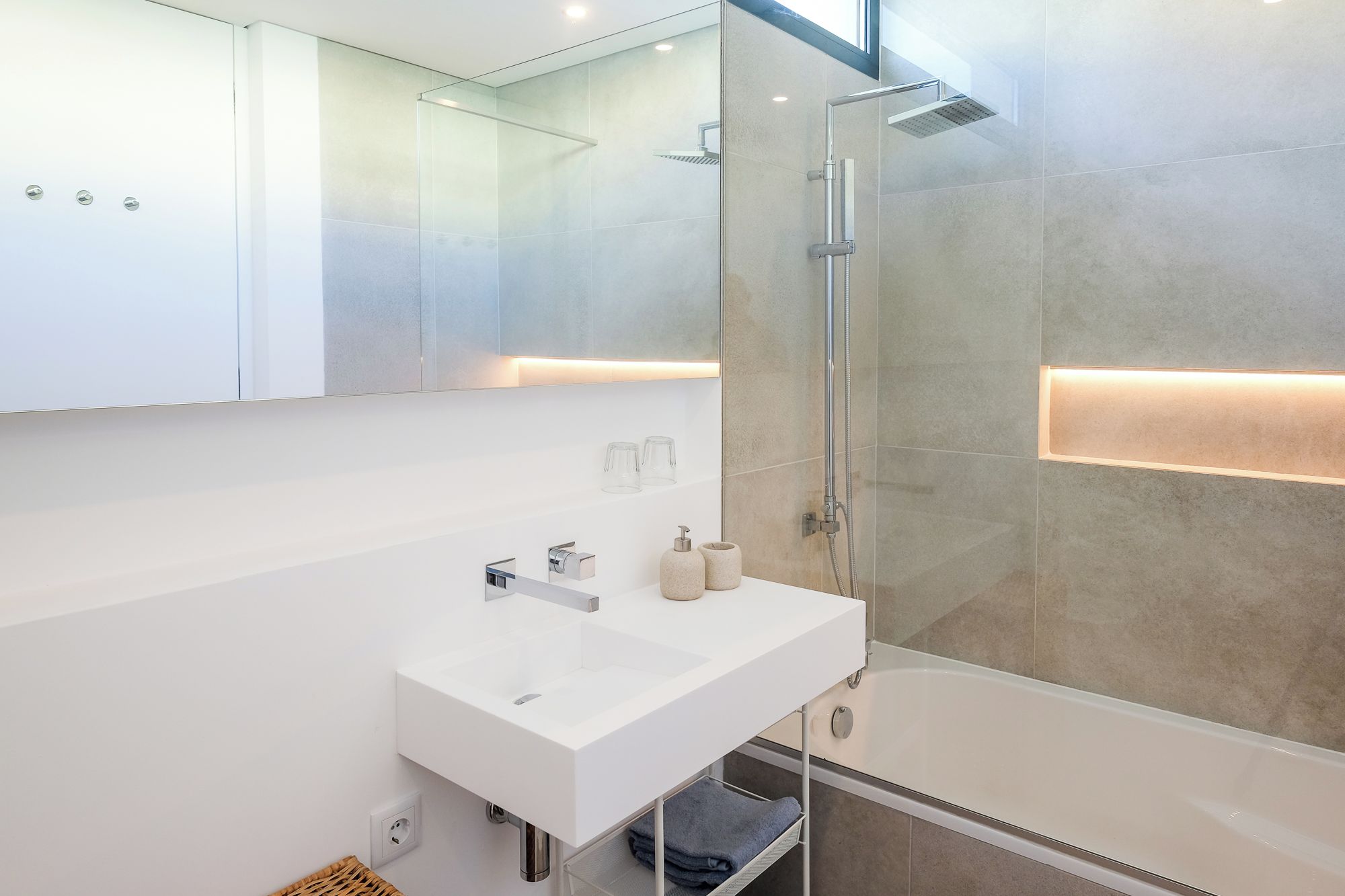 A modern bathroom with a white sink, glass shower enclosure, and a bathtub.