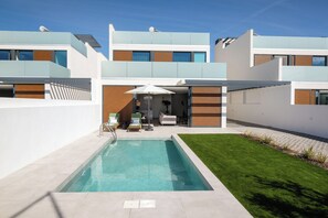 A modern residential building with a swimming pool, outdoor seating, and a well-maintained lawn. - Luxury 3-bedroom Privilege Casa do Colhereiro with Private Pool (Luz)