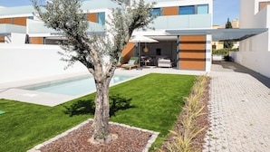 Een modern woonhuis met een zwembad, een verzorgd gazon en een patio.