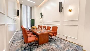Uma sala de conferências com uma mesa comprida, várias cadeiras e um tapete estampado.