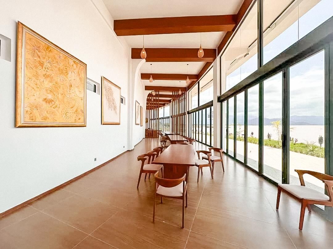 Um quarto amplo com uma mesa comprida e cadeiras, janelas grandes e obras de arte nas paredes.