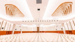 A large, modern auditorium with rows of white chairs and a central stage. - Arba Minch Conference Resort  (Arba Minch)