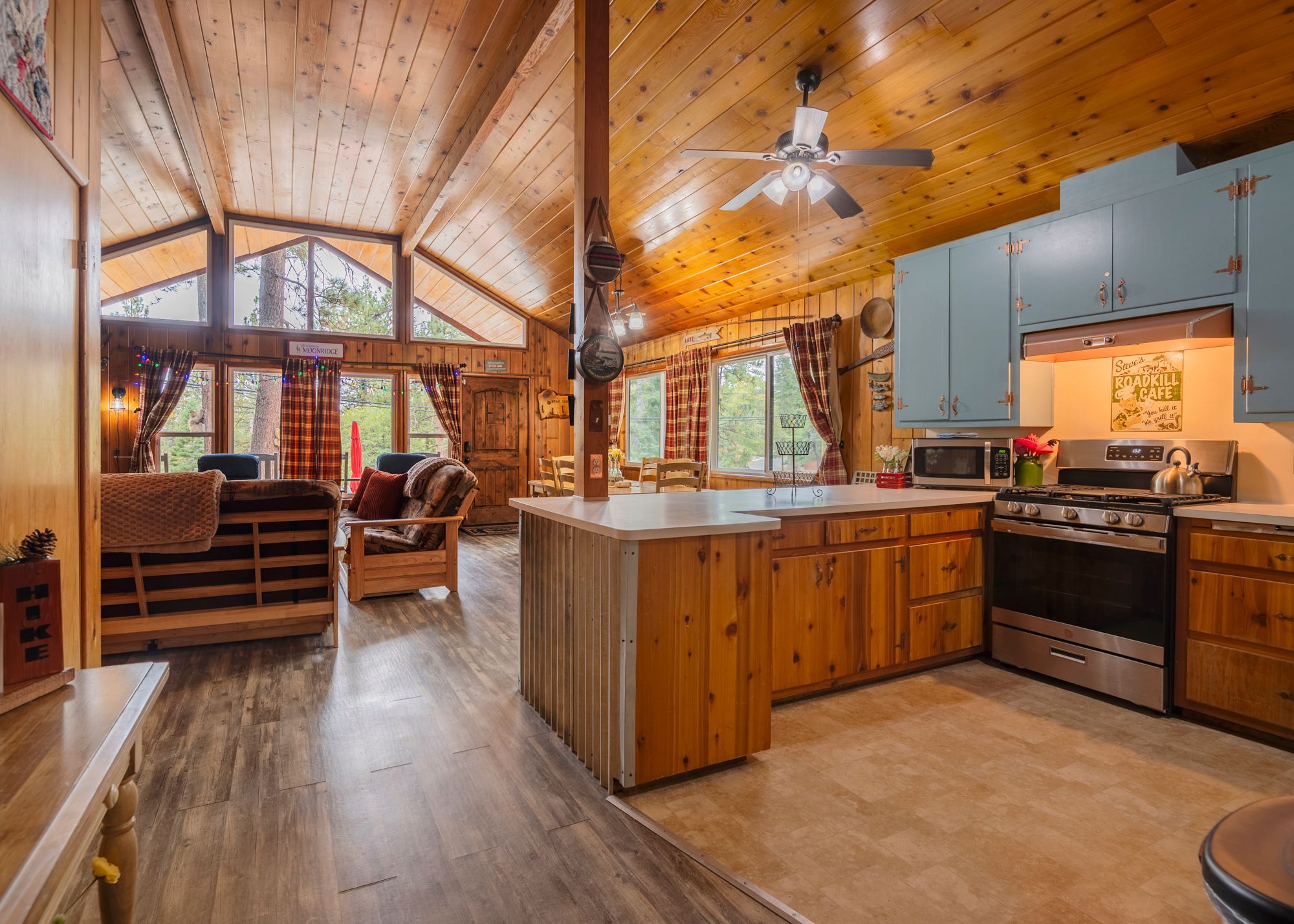 A cozy cabin interior with a dining area, kitchen, and a large window overlooking the outdoors.