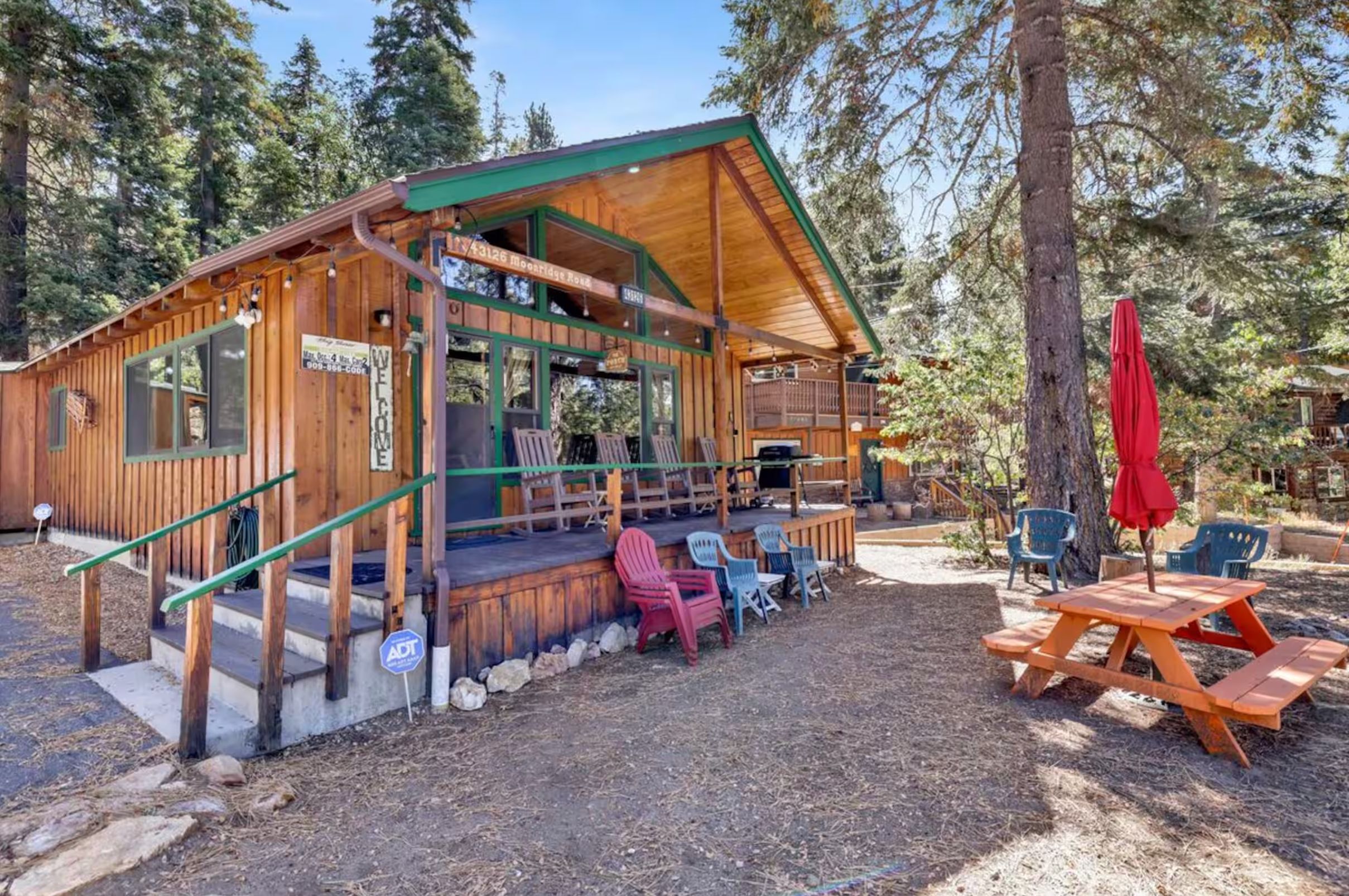 A wooden cabin with a porch, outdoor seating, and a picnic table.