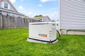 A GENERAC air conditioning unit in a backyard with a wooden fence and a house in the background. - Between the beaches extended family retreat-Gourmet Kitchen (York)
