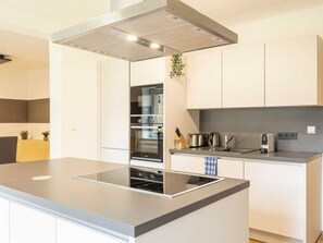 Una cocina moderna con una isla central, horno empotrado y electrodomésticos de acero inoxidable.