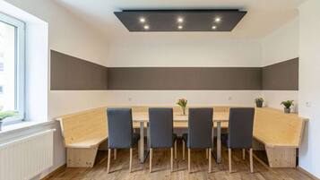 A conference room with a long table, four chairs, and a ceiling light fixture.