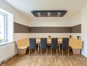 A conference room with a long table, four chairs, and a ceiling light fixture.