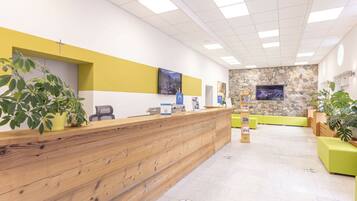 A reception area with a wooden reception desk, a stone wall, and a seating area with green cushions.