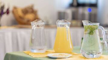 Una mesa con una jarra de jugo de naranja y otra de agua con hojas de menta.