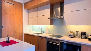 Una cocina moderna con gabinetes de madera, electrodomésticos de acero inoxidable, horno empotrado y lavavajillas.