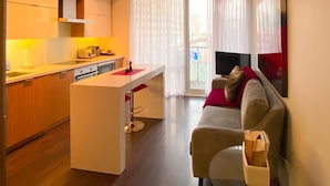 Una cocina moderna con una isla central, un área de comedor con un sofá y un televisor sobre un mueble.