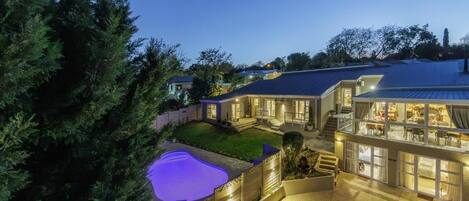 A residential property with a swimming pool, multiple levels, and a well-lit exterior.