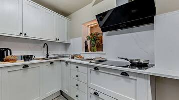 Une cuisine moderne avec des meubles blancs, une cuisinière noire et une fenêtre donnant sur une plante.