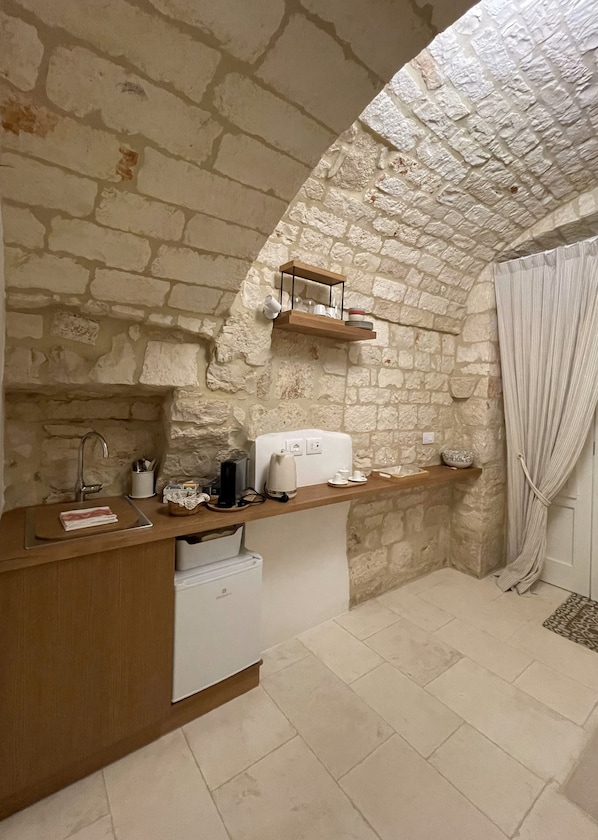 A kitchen with a stone wall, wooden countertop, and a built-in oven. - Vrbo Property (Locorotondo)