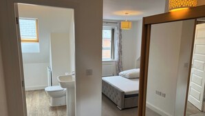 Een slaapkamer met een bed, een raam en een badkamer met toilet en wastafel.