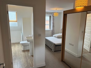 Une chambre avec un lit, une fenêtre et une salle de bain comprenant des toilettes et un lavabo.