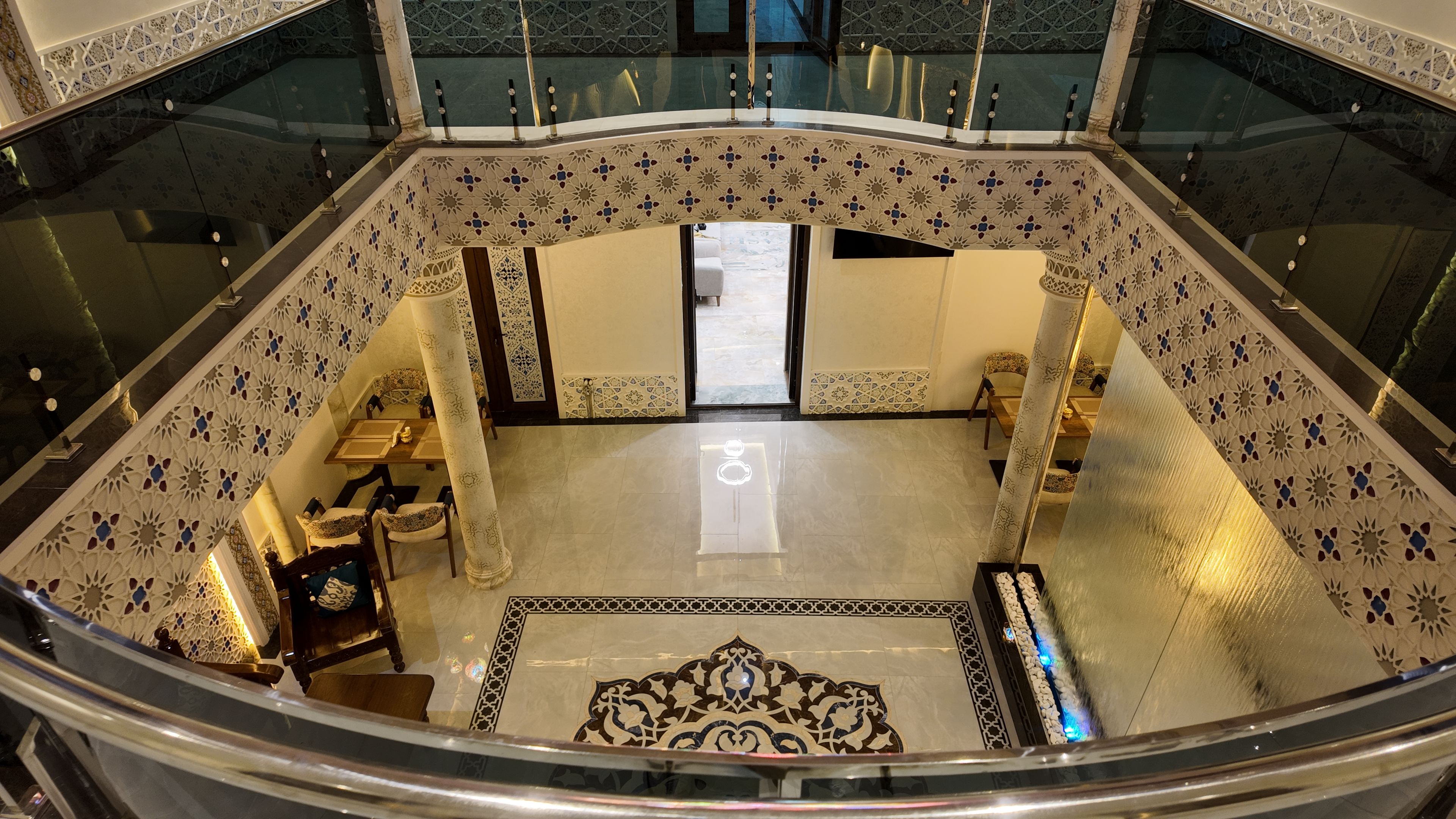 Un amplio atrio con techo alto, intrincados diseños de azulejos y una zona central abierta con asientos.