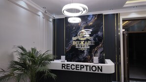 A reception desk with a sign that reads 'RECEPTION' and a wall with a 'DILKASH HOTEL' sign. - Hotel Dilkash (Samarkand)