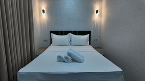 A hotel room with a large bed, two bedside tables, and a wall-mounted light fixture. - Hotel Dilkash (Samarkand)