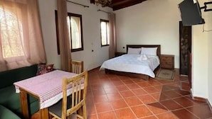 A room with a bed, a table with chairs, a green sofa, and a tiled floor. - Olea Azul (chefchaouen)